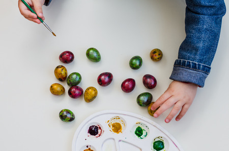 the child paint easter eggs by brush and paintsの写真素材