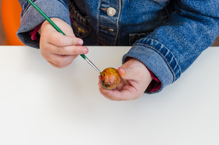 the child paint easter eggs by brush and paintsの写真素材