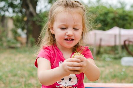 happy little girl playing hands with sand outdoorsの写真素材