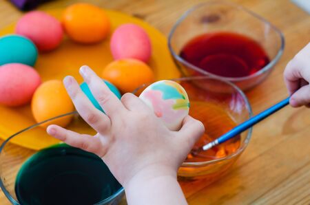 child paints an easter egg with paints and a brushの写真素材