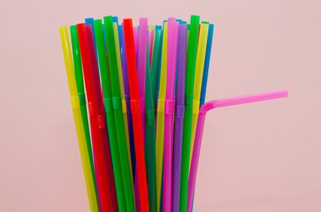 disposable plastic colored straws on a pink background, not environmentally friendlyの写真素材