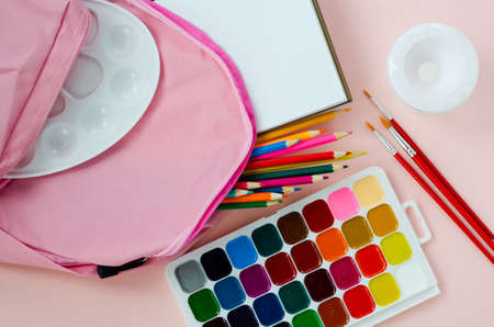 back to school, pink satchel with colored school supplies for drawing