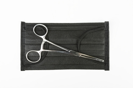 Forceps and black surgical mask. Medical concept.