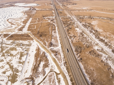 Snowy and frozen winter road with a moving car on it. Aerial view.