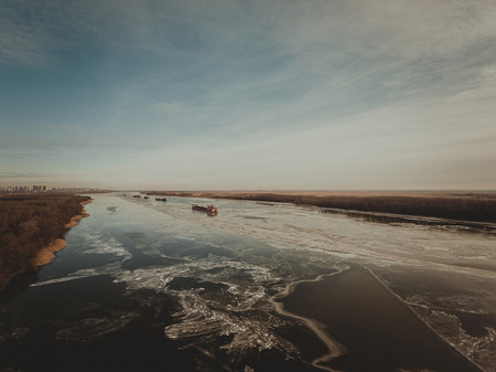Cargo ship on the ice river in winter. Aerial view.の写真素材