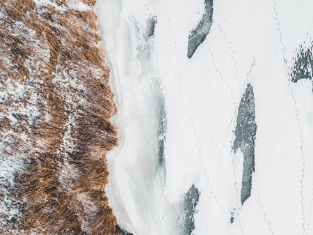 Yellow reed and frozen river in winter time. Aerial view.の写真素材