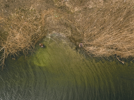 Fisherman with a spinning rod catching fish on a river. Hobby, leisure and active spring and autumn concept. Aerial view.の写真素材