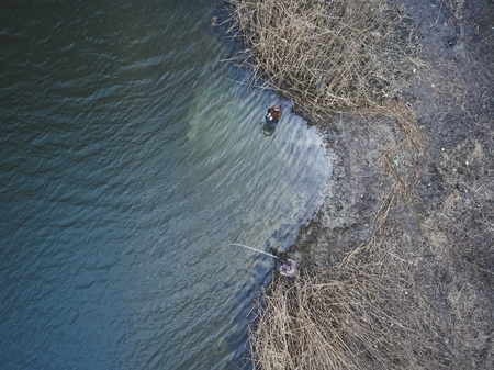 Fisherman with a spinning rod catching fish on a river. Hobby, leisure and active spring and autumn concept. Aerial view.の写真素材