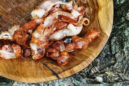 Stack of fried bacon strips in wooden bowl. Macro shot.の写真素材