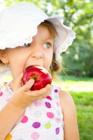 Portrait of a cute little girl with red appleの写真素材