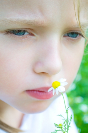 Closeup portrait of a cute little girl with daisyの写真素材