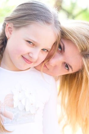 Bright picture of hugging mother and daughter outdoorsの写真素材