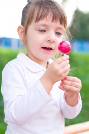 Happy little girl with lollipop outdoorsの写真素材