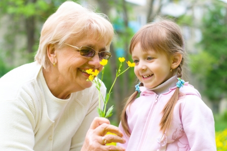 little girl giving her great grandmother yellow flowersの写真素材