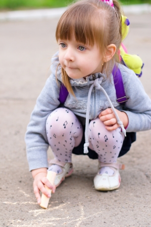 Cute little girl drawing with chalk outdoorsの写真素材