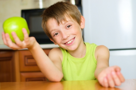 happy little boy with green apple indoorsの写真素材