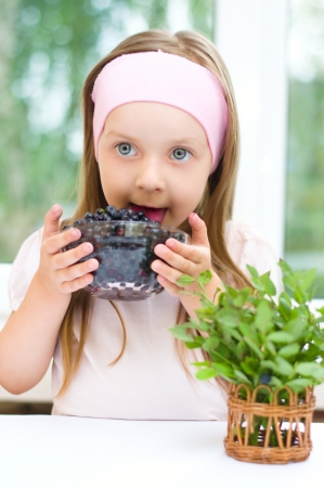 little girl with fresh blueberries indoorsの写真素材