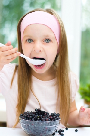 little girl with fresh blueberries indoorsの写真素材