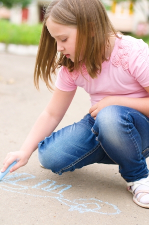 Cute little girl drawing with chalk outdoorsの写真素材