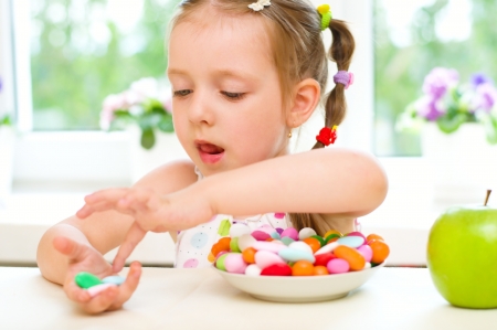 Cute little girl choosing between apples and sweetsの写真素材