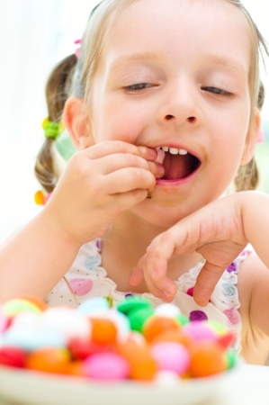 happy little girl eating sweets color candiesの写真素材