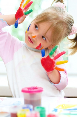 Cute little girl with painted hands indoorsの写真素材