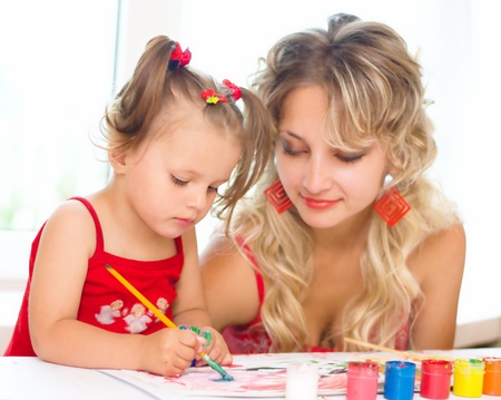 Child with mother painting indoorsの写真素材