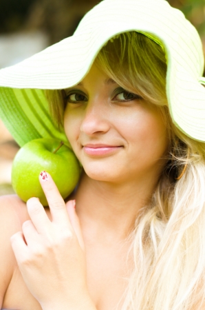 summer portrait of beautiful woman with green appleの写真素材