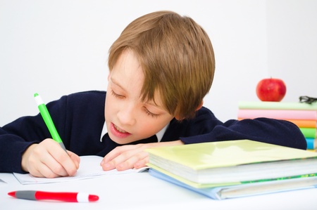 Little schoolboy writing homework from school in workbookの写真素材