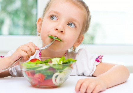 Little cute girl eating vegetable saladの写真素材
