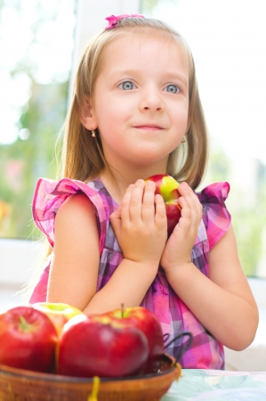 cute little girl holding apples at homeの写真素材