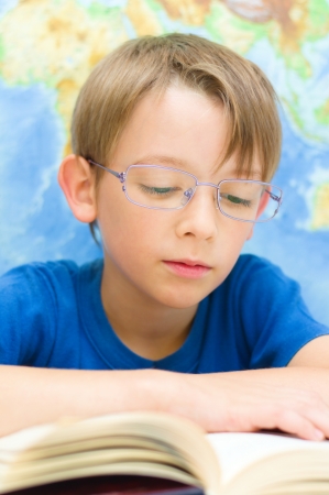 schoolboy reading a book in front of world mapの写真素材