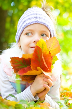 cute little girl with autumn leaves in the beauty parkの写真素材