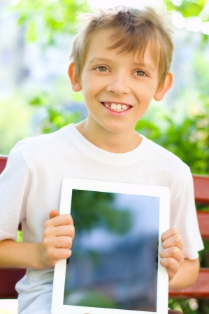 cute little boy with tablet computer outdoorsの写真素材