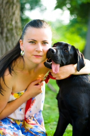 Young woman hugging black dog outdoorsの写真素材