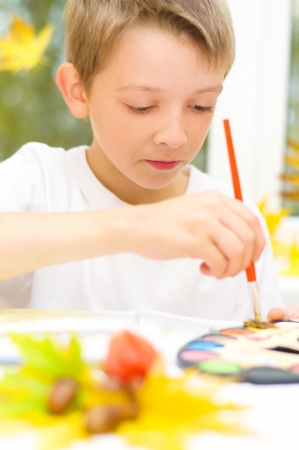 little boy painting with paintbrush and colorful paintsの写真素材
