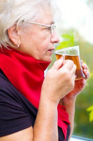 portrait of a old woman drinking tea, autumn backgroundの写真素材