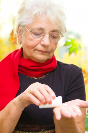 senior woman holding a pill in her hand, preparing to eat that - part of a series.の写真素材