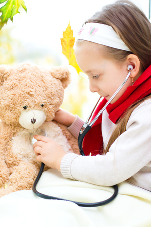Little girl is examining her teddy bear using stethoscopeの写真素材