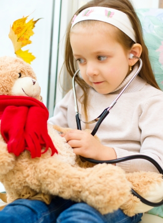 Little girl is examining her teddy bear using stethoscopeの写真素材