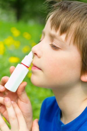 little boy spraying his nose outdoorsの写真素材