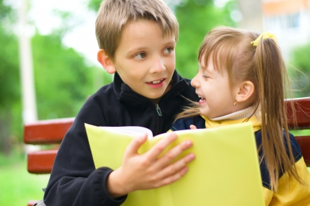 Lovely children - brother and sister, reading a book at the parkの写真素材