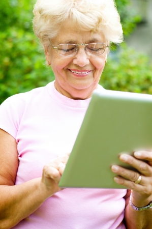 Portrait of an elderly woman working on a tablet and smiling, outdoorsの写真素材