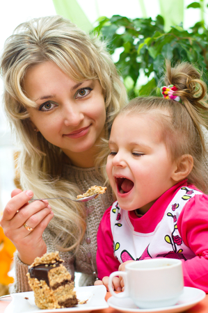 mother is feeding her daughter at homeの写真素材