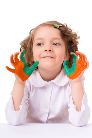cute cheerful girl showing her hands painted in bright colors, isolated over whiteの写真素材