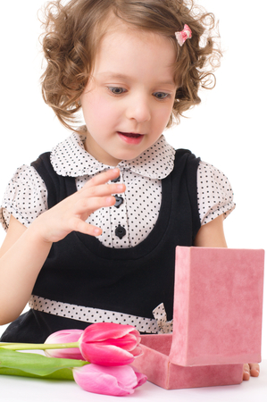 happy little girl is holding bouquet of tulips and gift box, isolated over whiteの写真素材