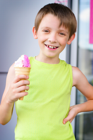 young boy eating a tasty ice cream outdoorsの写真素材