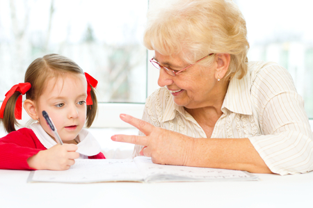 Grandmother teaches to write letters her granddaughterの写真素材
