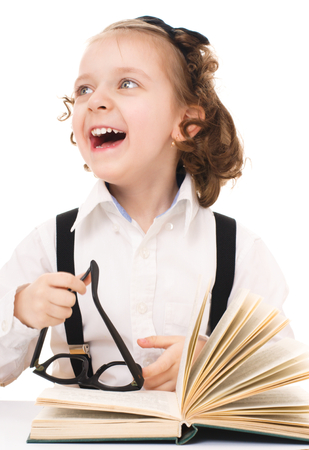 little girl is reading a book, isolated over whiteの写真素材