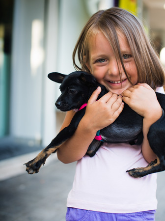 portrait of a cute little girl holding dog outdoorsの写真素材